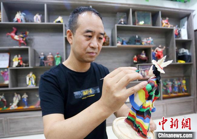 圖為安秋平正在創(chuàng)作代表隴南文縣民俗的《白馬人》作品。 高展 攝 圖為安秋平正在創(chuàng)作代表隴南文縣民俗的《白馬人》作品。 高展 攝