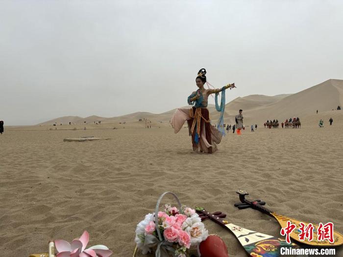 圖為2023年4月底，敦煌大漠“逐舞者”奧楠在鳴沙山月牙泉景區視頻直播敦煌舞?！●T志軍 攝